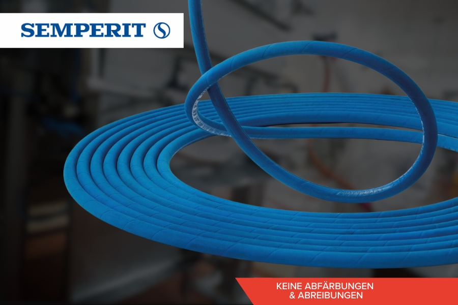 Ein blauer Industrieschlauch ist ordentlich vor einem unscharfen Hintergrund aufgerollt . Das Semperit-Logo ist auf der obere linke Seite zu sehen, während auf einem roten Banner unten rechts steht: „KEINE ABFÄRBUNGEN & ABREIBUNGEN“.