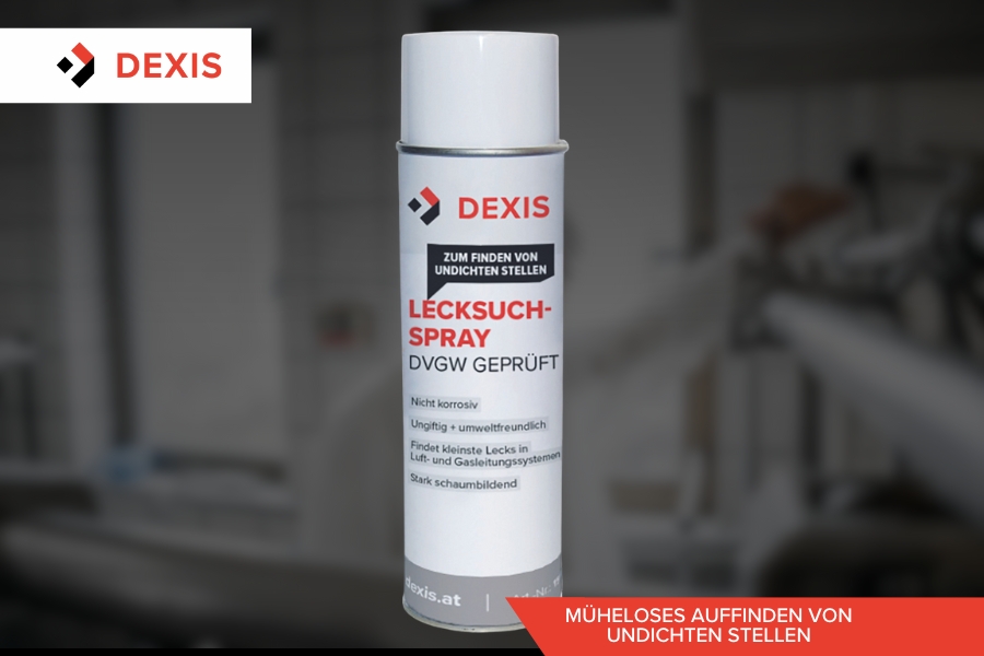 Eine Dose Dexis Lecksuch-Spray steht zentriert vor einem unscharfen Industriehintergrund. Die weiße Dose trägt einen rot-schwarzen Text, das DEXIS-Logo ist prominent in der oberen linken Ecke platziert.